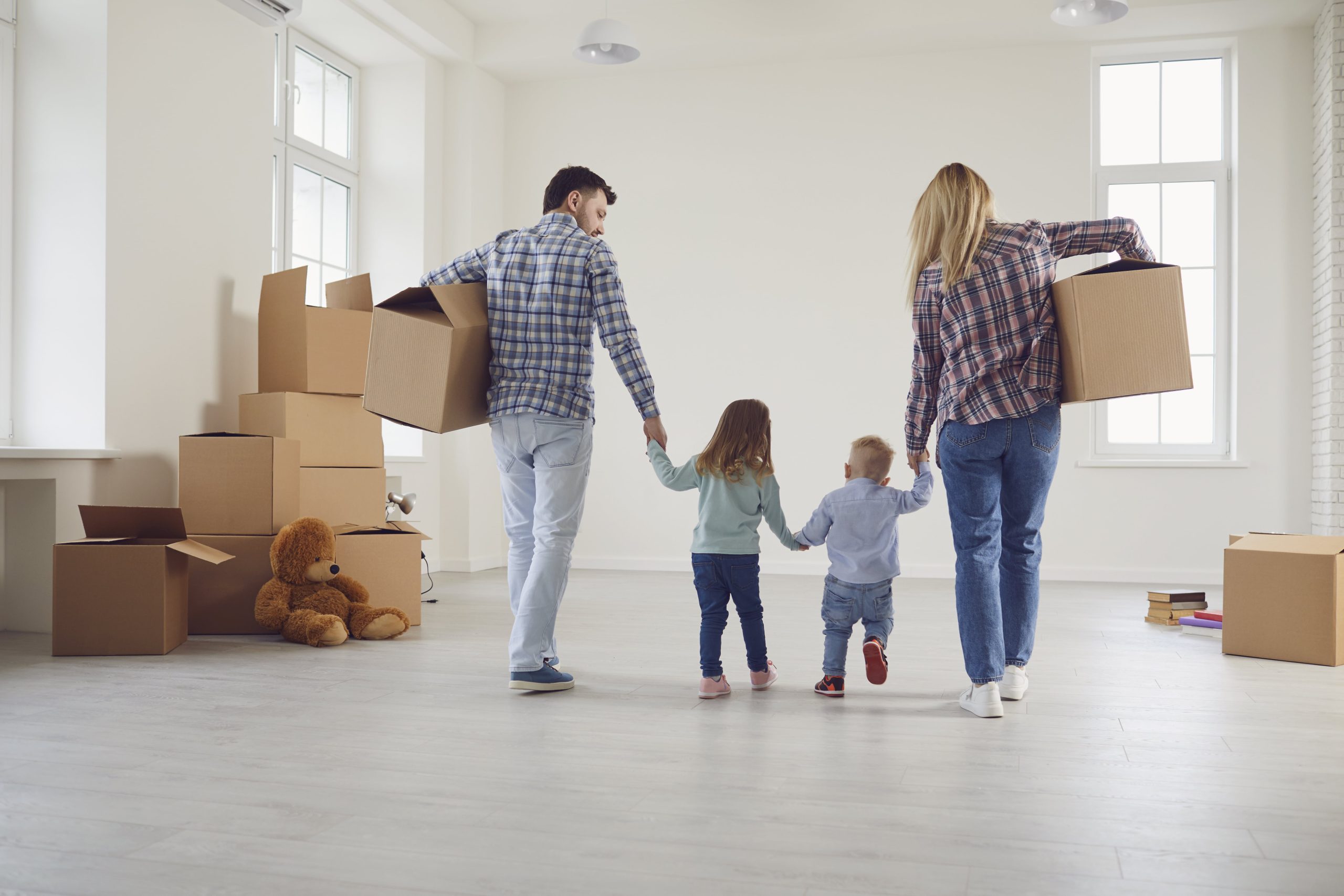 Happy family with children moving with boxes in a new house.